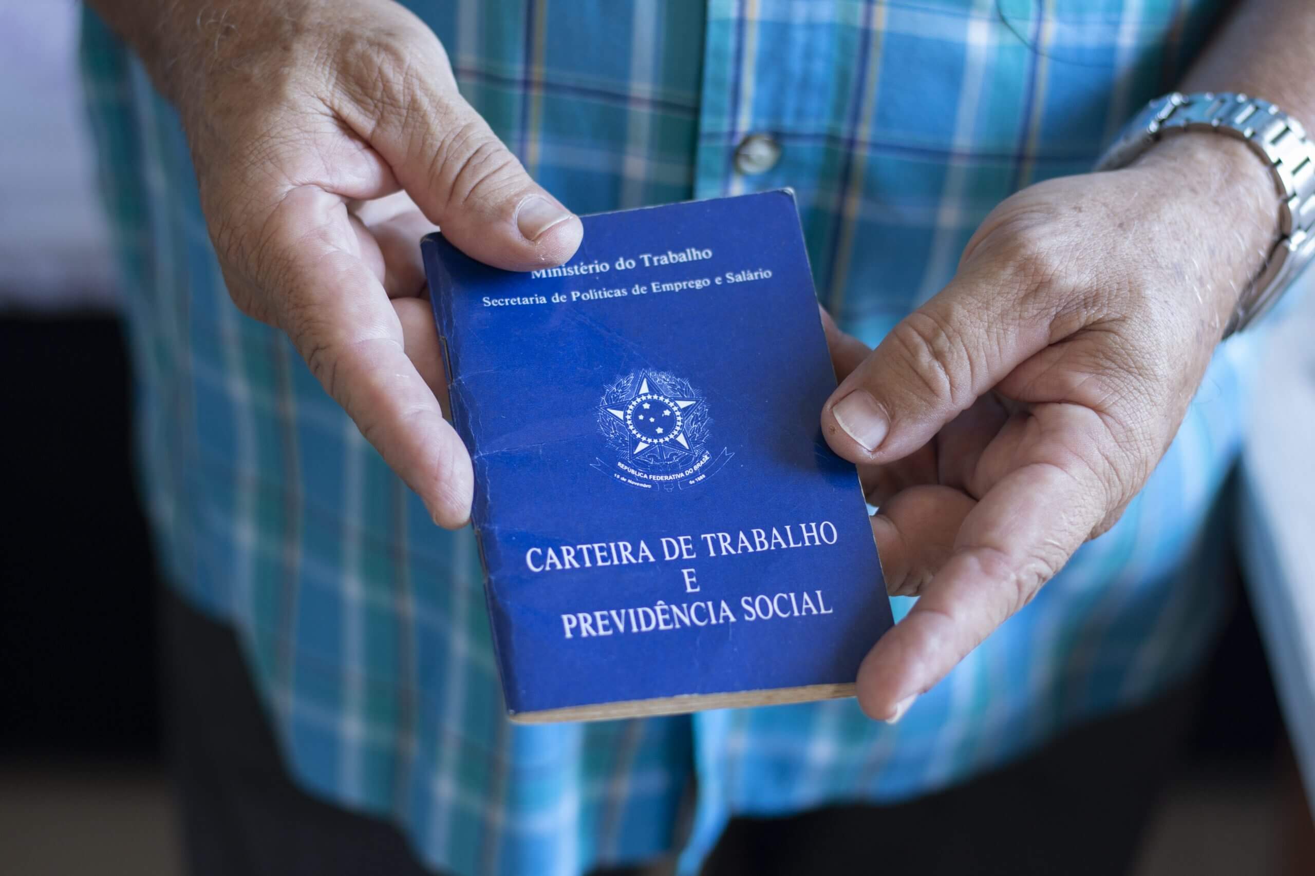 Imagem de um homem segurando a Carteira de Trabalho e Previdência Social